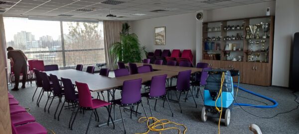 Sprzątanie sali konferencyjnej w biurze przy pomocy odkurzacza piorącego