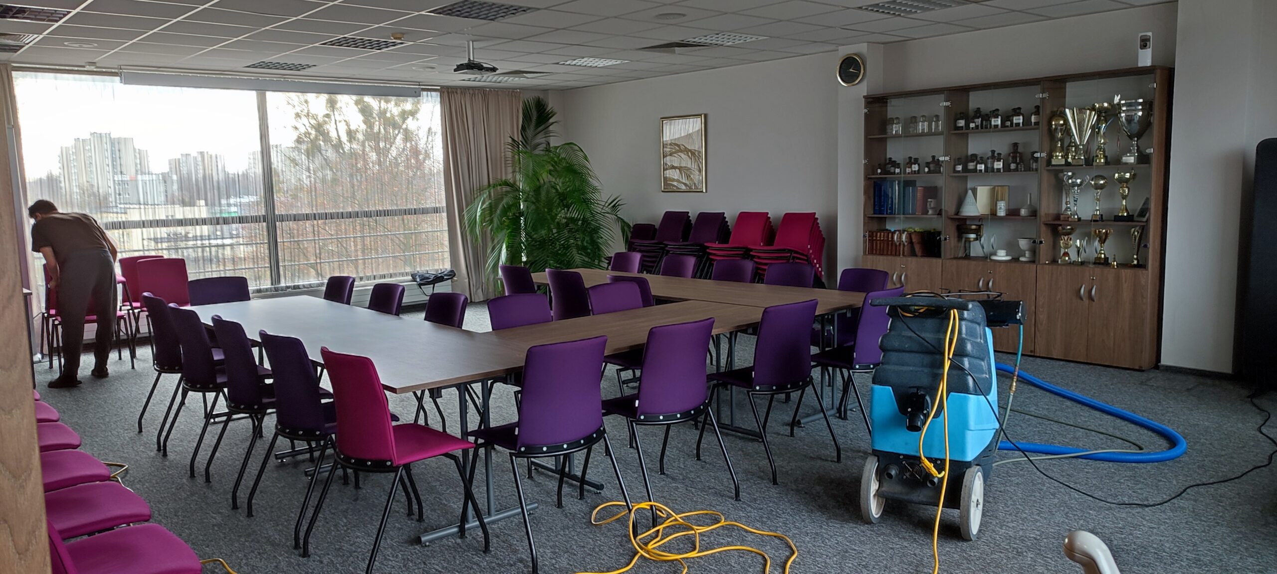 Sprzątanie sali konferencyjnej w biurze przy pomocy odkurzacza piorącego