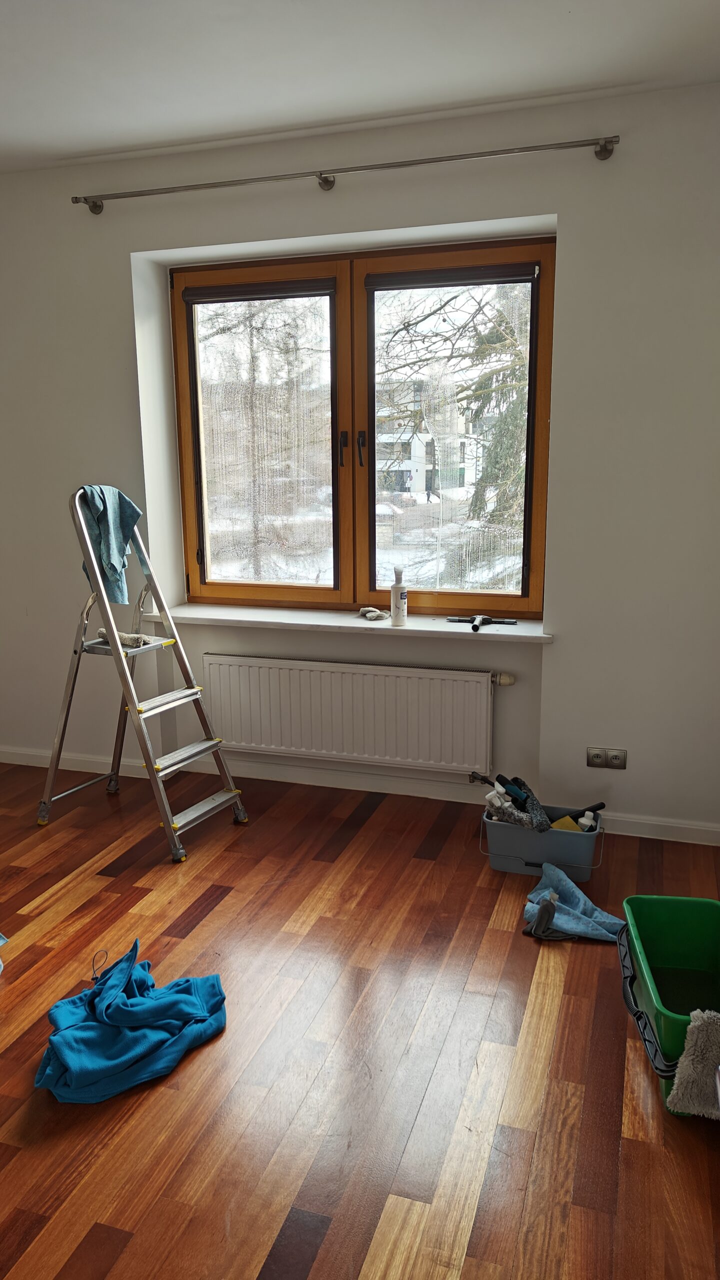 mycie okna z brązowymi ramami w mieszkaniu w Warszawie