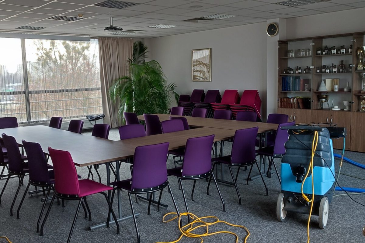 Sprzątanie sali konferencyjnej w biurze przy pomocy odkurzacza piorącego