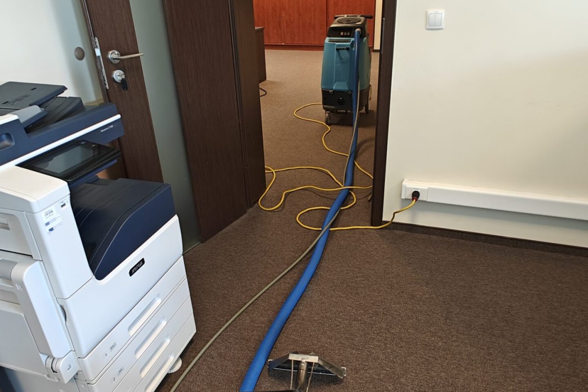 sprzątanie pokoju biurowego niebieskim odkurzaczem piorącym